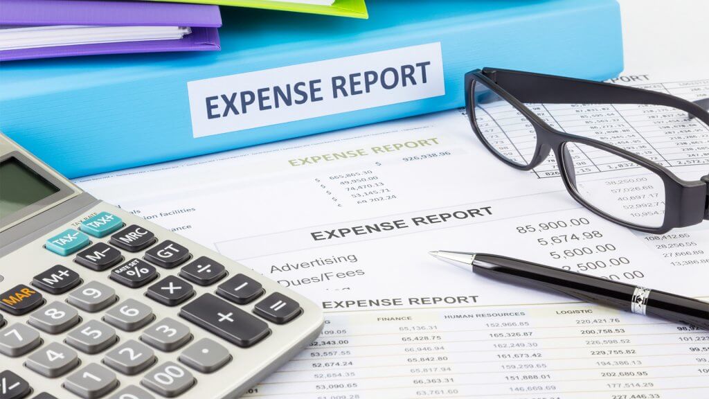 Expense reports and folders, with a calculator, pen, and glasses nearby
