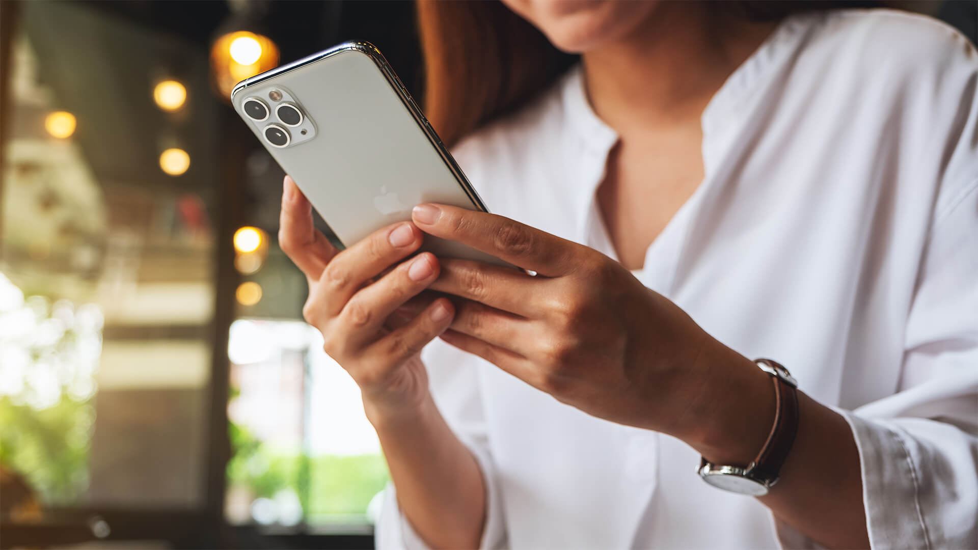 A woman holding and using Iphone 11 Pro Max smart phone